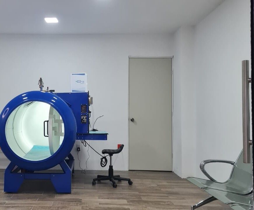 Sala de tratamiento con la cámara hiperbárica, su panel de control y el área de espera.